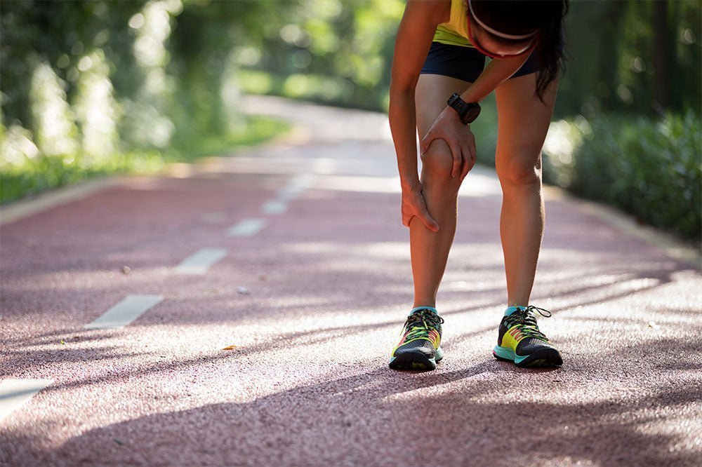 Läuferin unterbricht den lauf und hält sich schmerzerfüllt das Schienbein